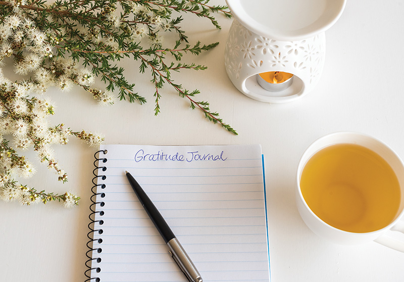Gratitude journal with pen, cup and flowers