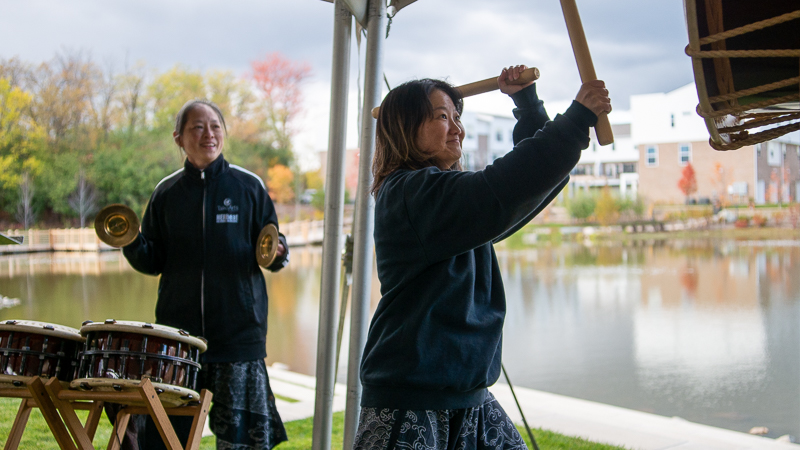 Two women play instruments at the dedication of Sakura Gardens