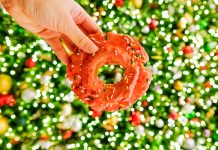 13 Things To Do In Metro Detroit This Weekend (Nov. 14-16) A donut held in front of Christmas decorations.