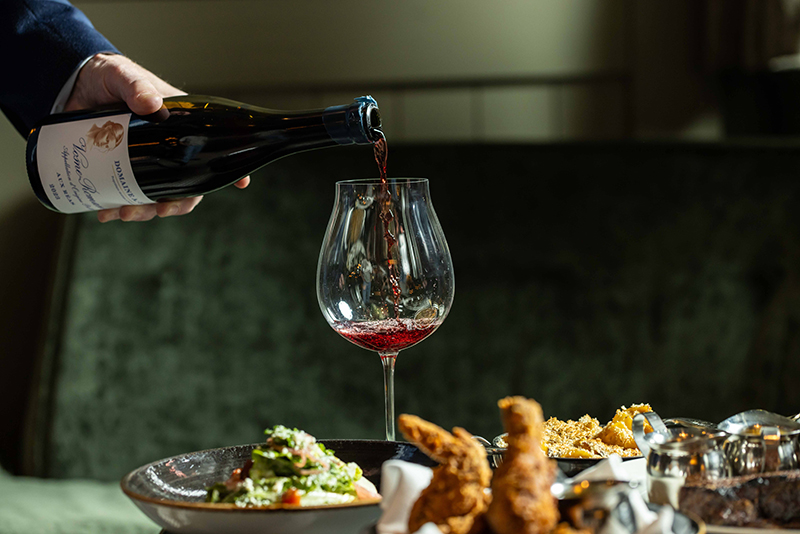 A wine glass being filled with red wine.