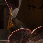 A chef sprinkles salt on a ribeye steak