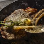 A steak being finished with brown butter.