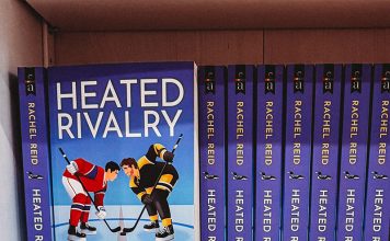 Multiple copies of 'Heated Rivalry' on a bookshelf.