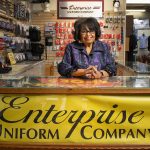Enterprise Uniform Co.: An Unsung Hero for Detroit’s Frontline Workers Lynne Burgess-Holmes posing at her counter.